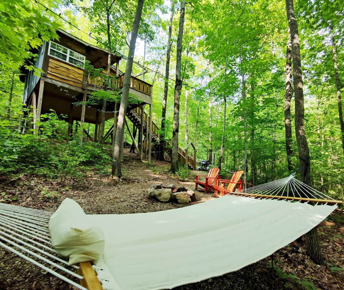 Dove treehouse seen from the hammock, past the fire ring and red Adirondack chairs